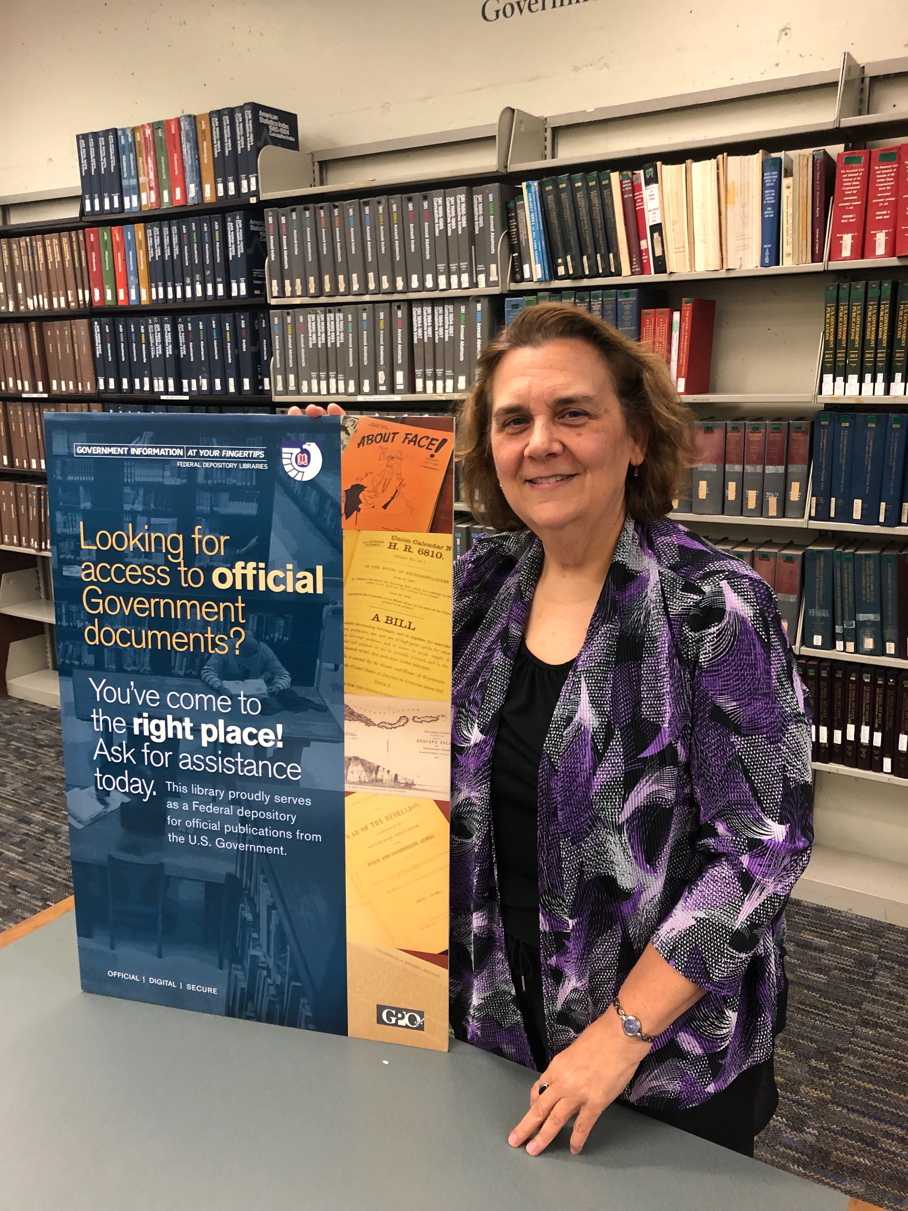 Karina Ricker poses with a Government Information poster