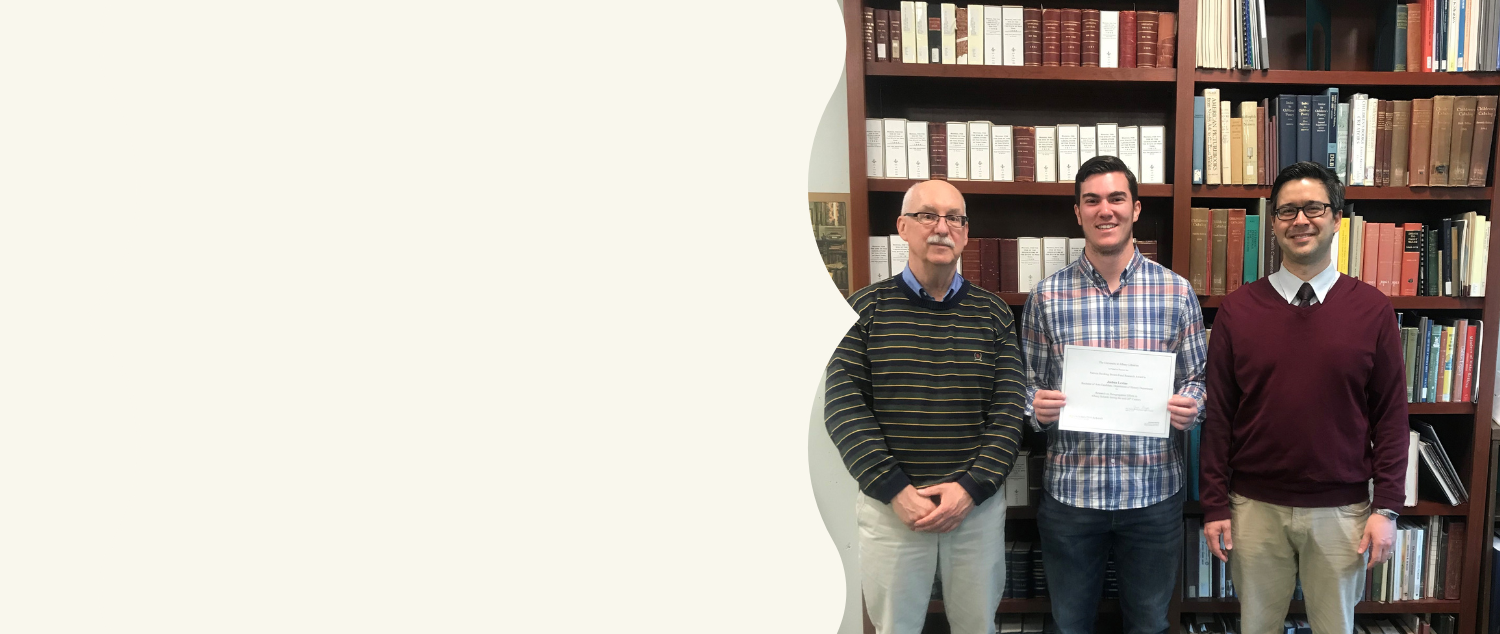 Student winner with two mentors. Picture is taken in front of a bookshelf filled with books. 