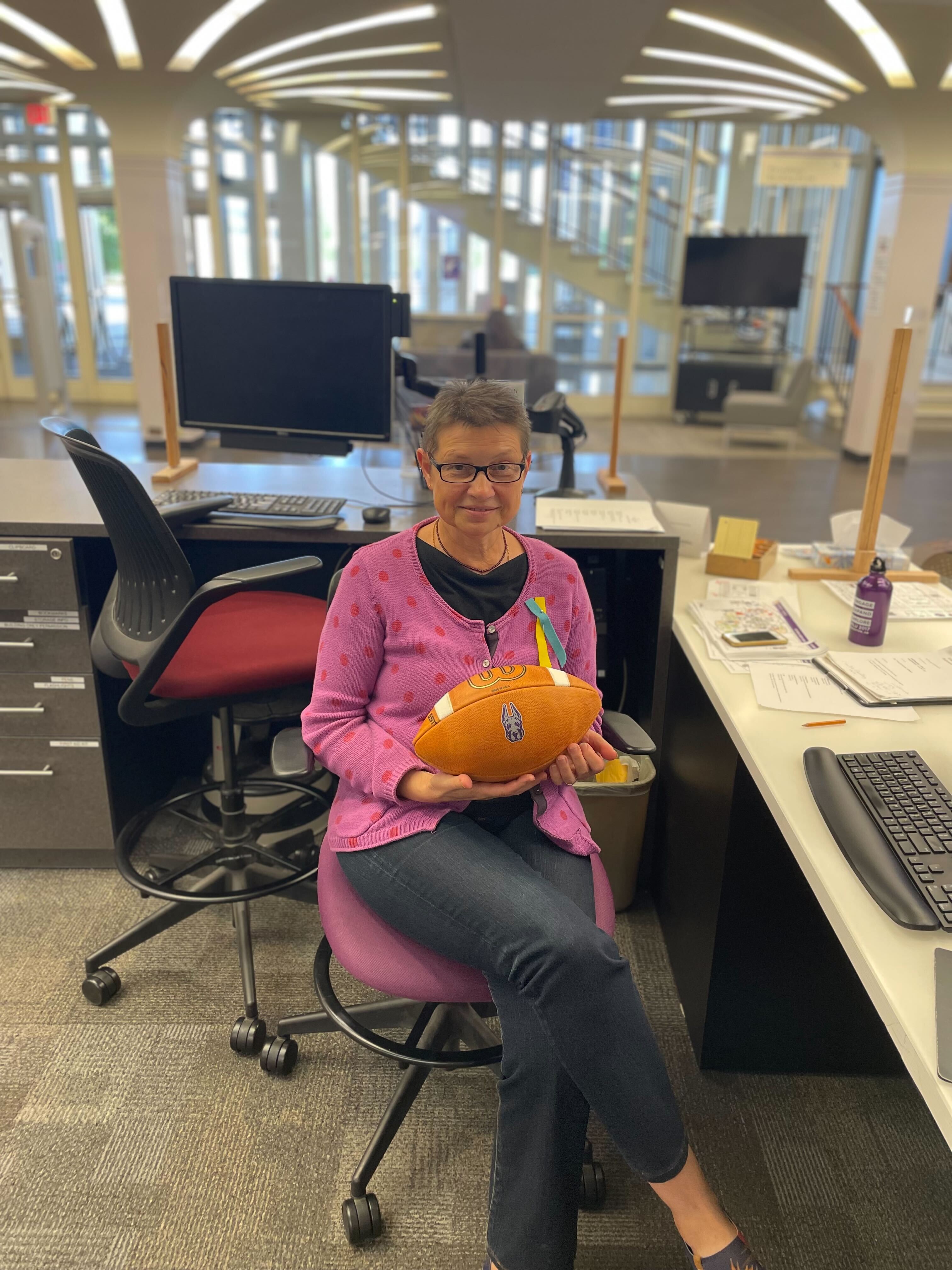 Irina Holden at the reference desk with a UAlbany football