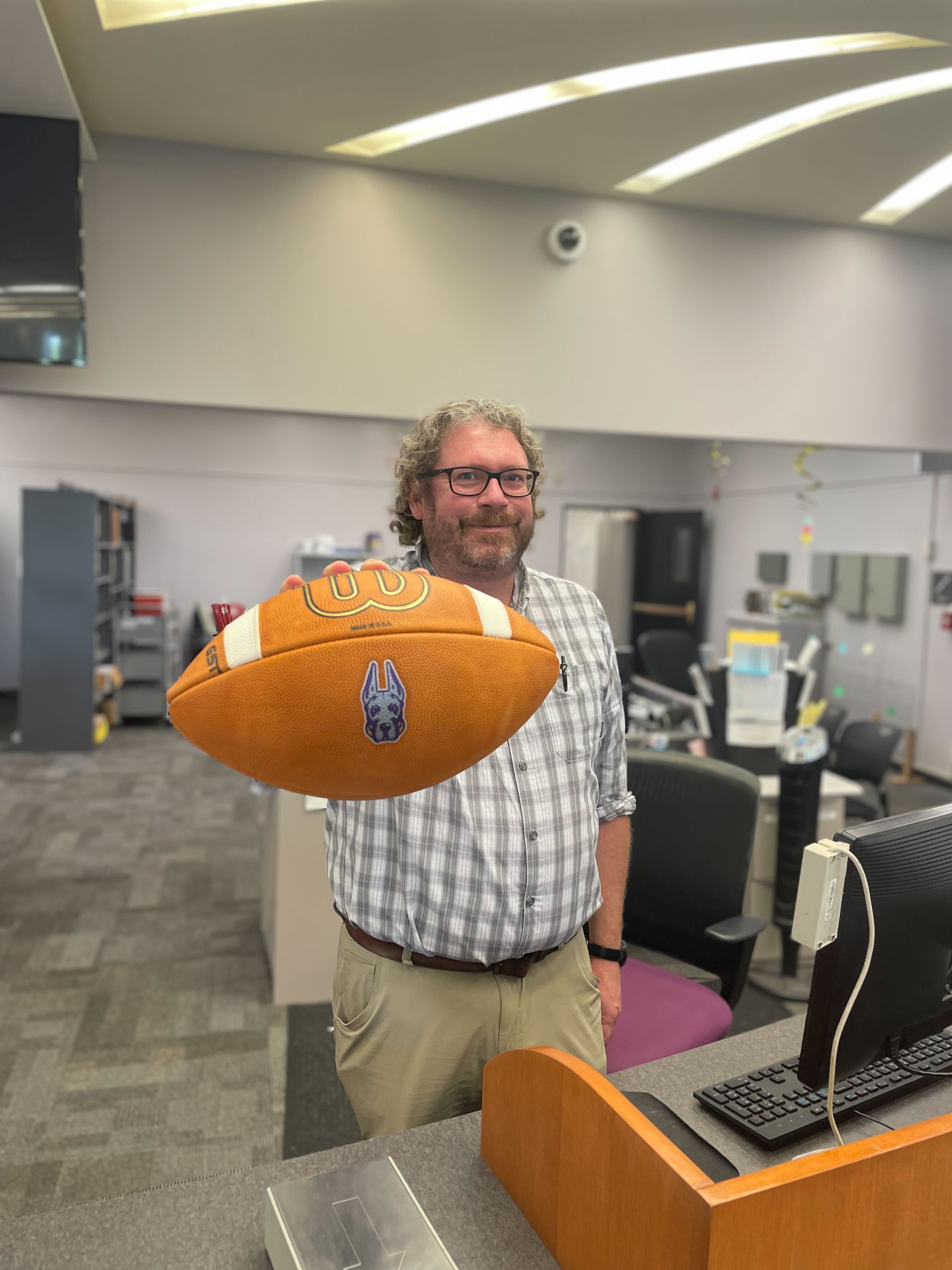 Robert Sheedy at the front desk with a UAlbany football