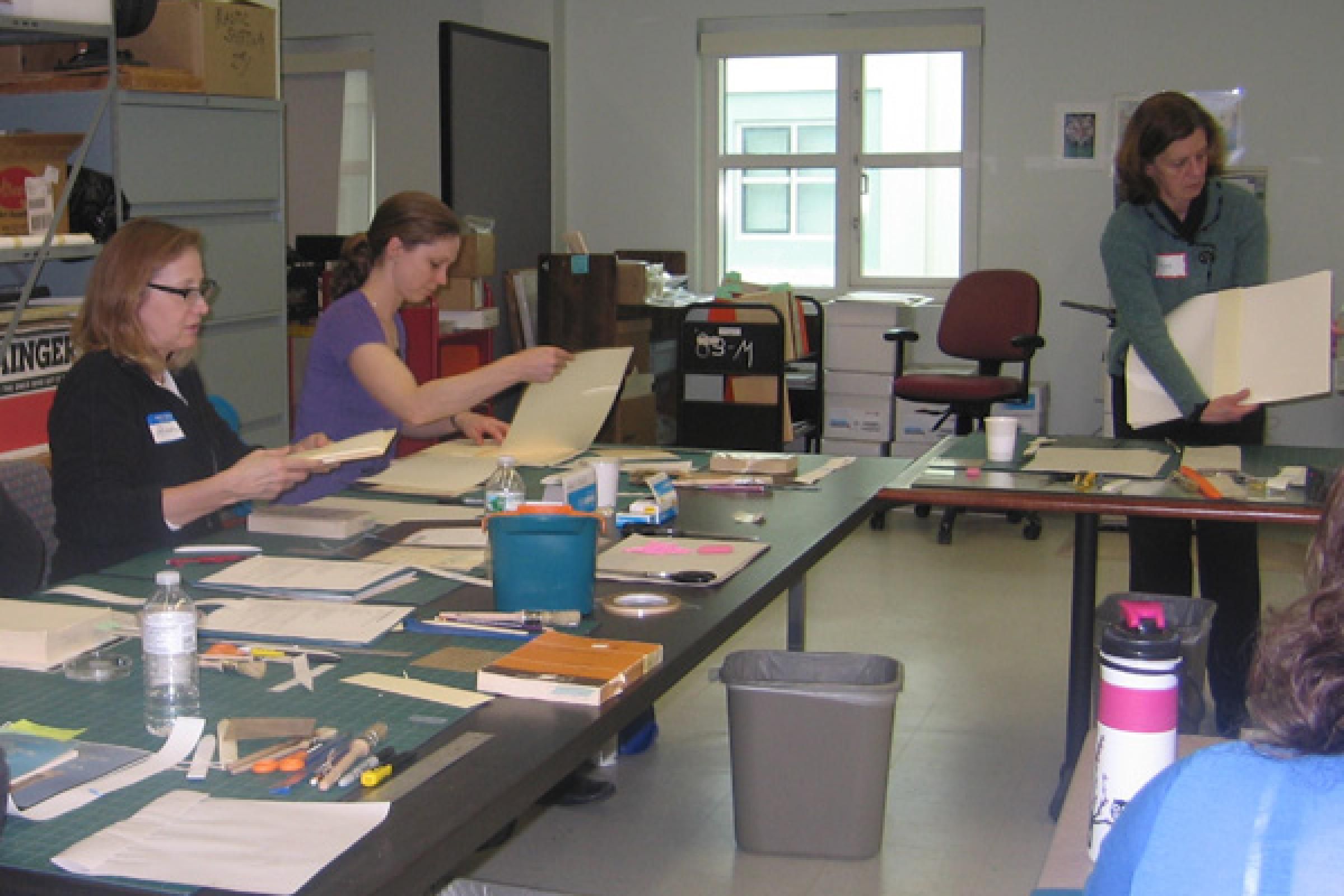 Students consider their own paperbacks, materials and tools as Ann explains the repair process.