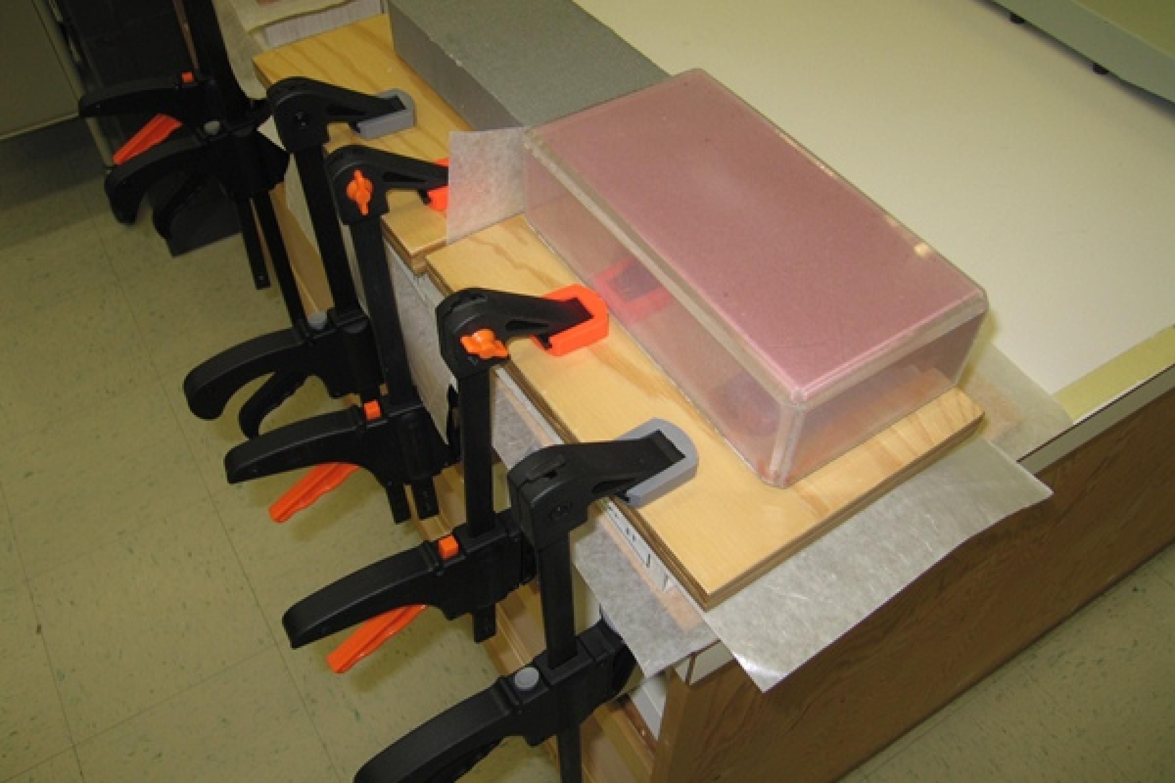 Clamped boxes drying under weights